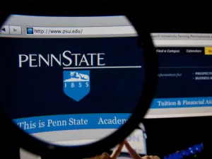 Penn State homepage on a monitor screen through a magnifying glass 