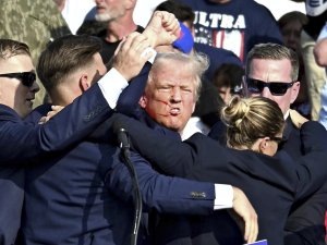Former President Donald raises his fist as he is surrounded by Secret Service agents in Bulter Pennsylvania