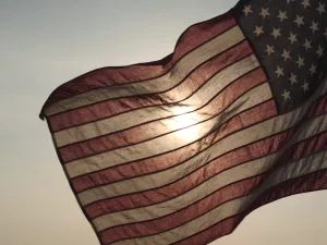 American flag waving with the sun shining through it