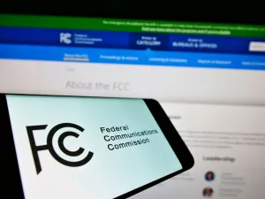 Mobile phone with seal of US agency Federal Communications Commission FCC on screen in front of web page