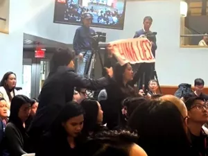 Harvard student Cosette Wu disrupts a speech by Chinese Ambassador Xie Feng at the Harvard Kennedy School, holding a sign that reads "China Lies" on April 20, 2024. Wu then has her arm pulled down and is removed from the room by a fellow student who supports the Chinese Communist Party.