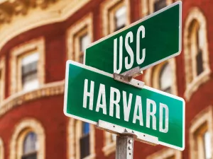 Street sign reading Harvard and USC, concept indicating colleges are at a crossroads