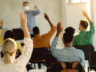 Students raising hands in a classroom - CREDIT Drazen Zigic Shutterstock