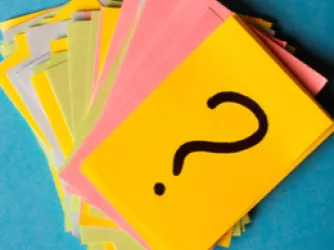 A stack of colored notecards, the top one showing a question mark. 