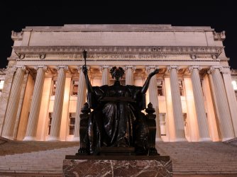 Alma Mater on the steps of the Columbia University library at night