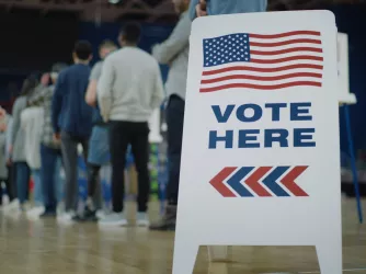 Vote here sign on the floor next to people waiting in line to vote