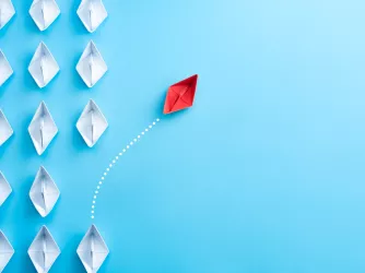 White paper ships on a blue background with a single red ship sailing away unique