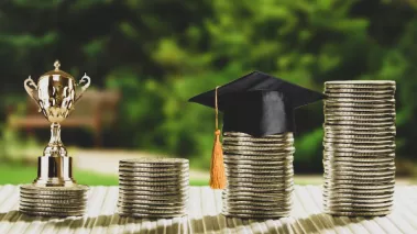 Stacks of coins with graduation cap and trophy