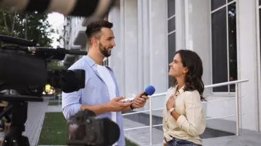 Professional journalist taking interview in front of video cameras outdoors 