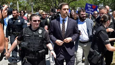 Christopher Rufo is escorted away from protesters by police