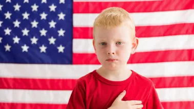 Boy in front of American flag with hand over heart