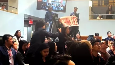 Harvard student Cosette Wu disrupts a speech by Chinese Ambassador Xie Feng at the Harvard Kennedy School, holding a sign that reads "China Lies" on April 20, 2024. Wu then has her arm pulled down and is removed from the room by a fellow student who supports the Chinese Communist Party.