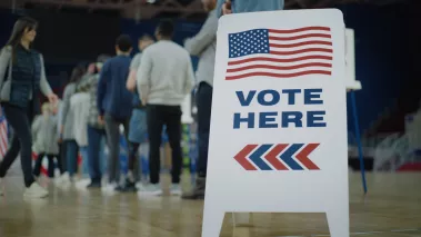 Vote here sign on the floor next to people waiting in line to vote