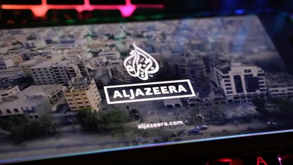 Smartphone screen on computer keyboard with logo lettering of Al Jazeera arabic television with Gaza Israel conflict report 