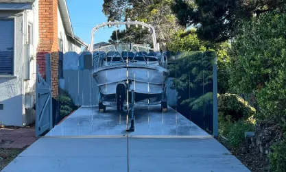 Boat parked in a driveway painted on the fence of that same driveway.