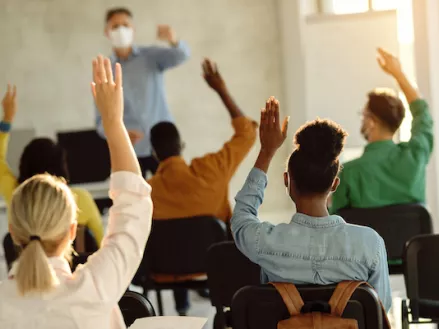 Students raising hands in class showing academic freedom rights