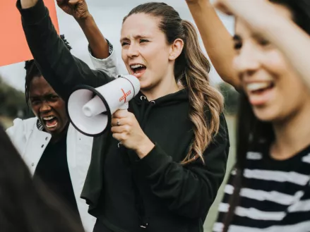 Peaceful protest with young woman speaking into a megaphone.