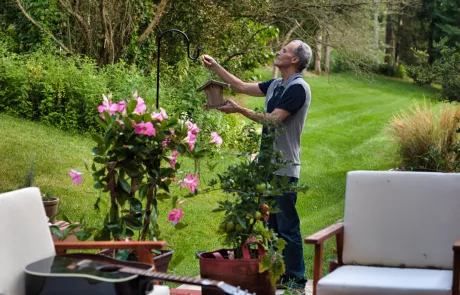 Joe Gow hangs a birdhouse in his backyard