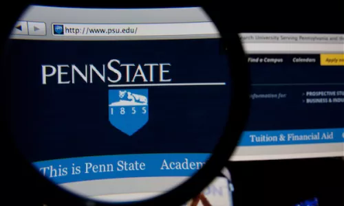 Penn State homepage on a monitor screen through a magnifying glass 