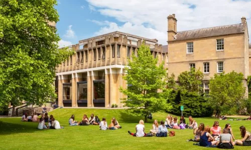 Students sitting together on grass near a college building