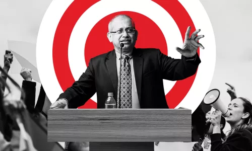 Man at a podium standing in front of a red bullseye 