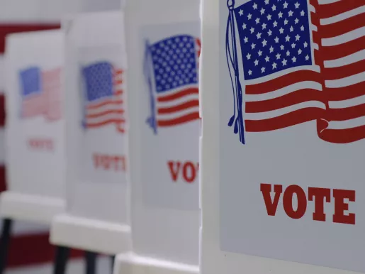 Straight on row of voting booths at polling station during American election with a US flag in background