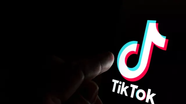 Finger touching a screen display with the TikTok symbol