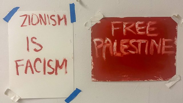 Two paper signs posted on a door, one reading "Free Palestine" and the other "Zionism is Fascism"